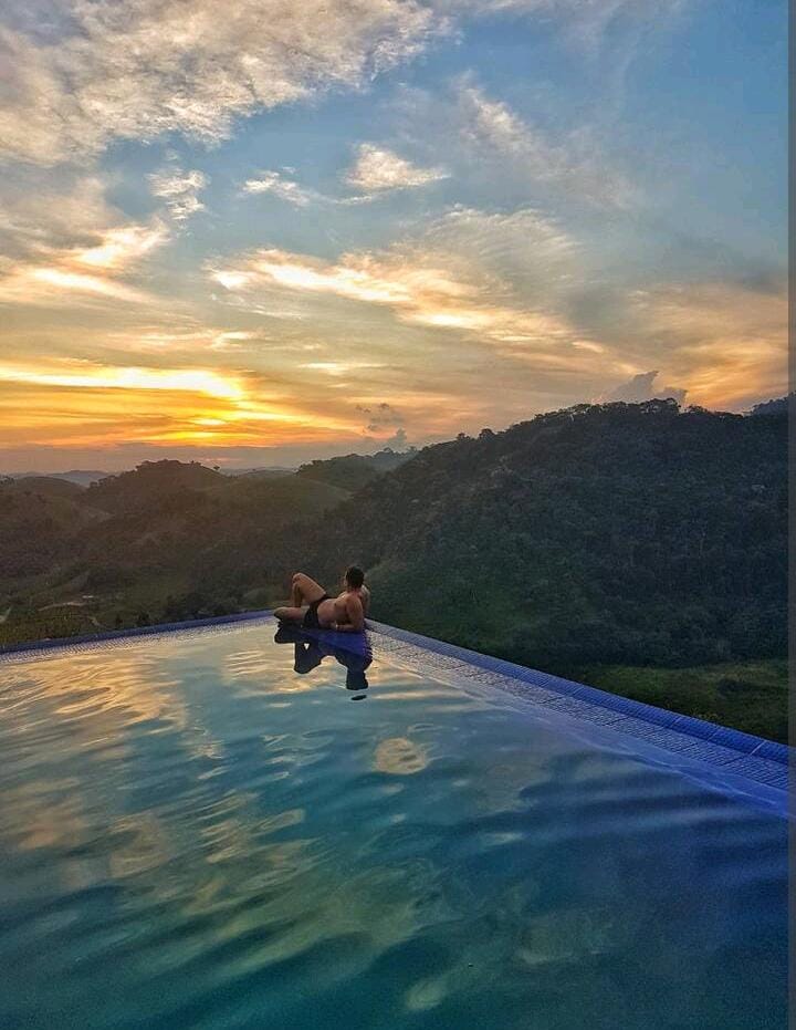 Um fogo lenhoso brilha num lar de pedra e madeira, arredor de dois sofás bem iluminados.
